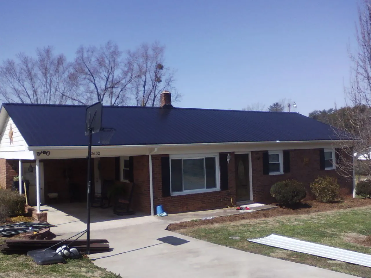Finished dark blue metal roof on a brick ranch with a carport in Townville