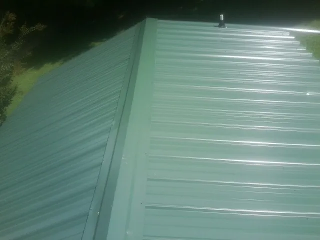 New green metal panels meeting at the ridge of a roof — Flat Roof Repair work by our crew in Townville