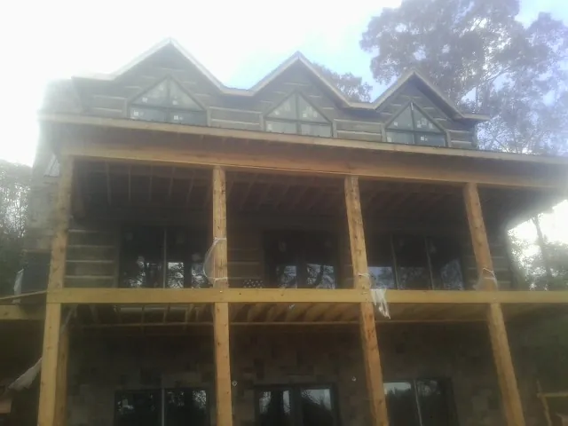 Dormers and porch framing on a large log home under construction — Roof Coating work by our crew in Townville