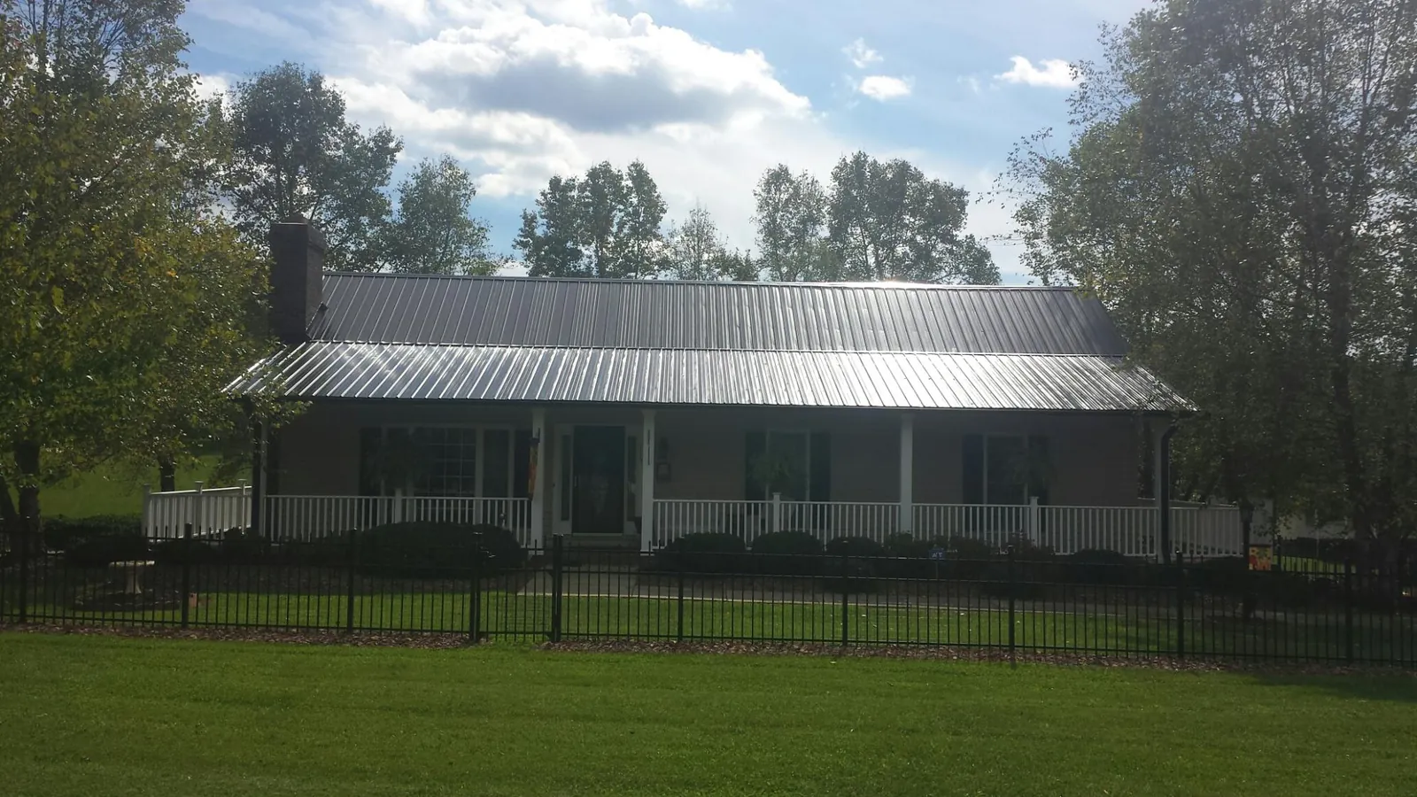 Gray metal roof on a brick ranch with a full width front porch — Gutter Guard Installation work by our crew in Townville