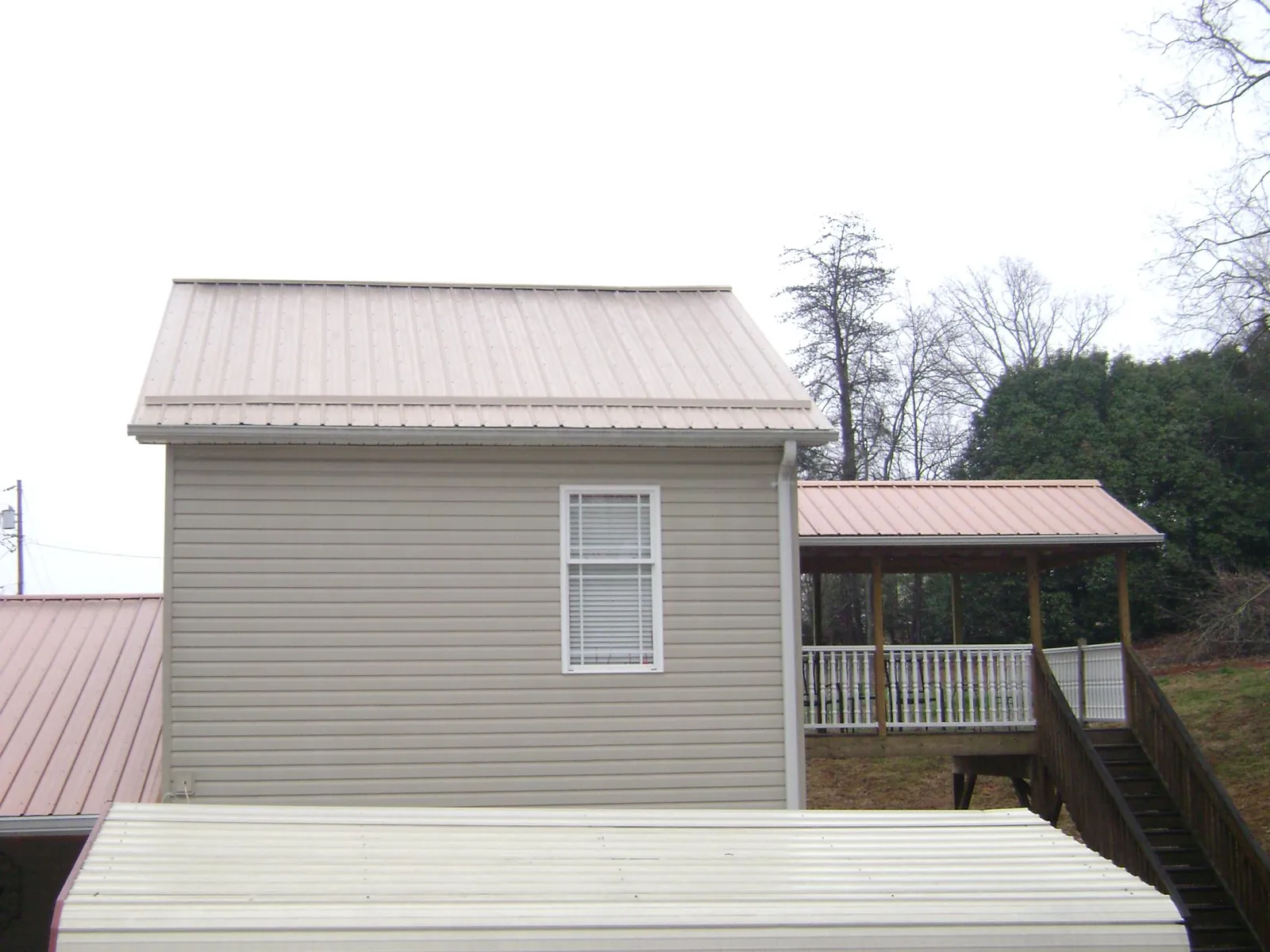 Tan metal roofs on a two story addition and attached porch, from a Roof Replacement job in Townville